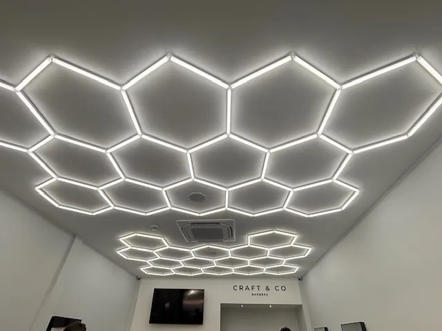 Hexagonal LED ceiling light grid installed across the ceiling of a barber shop